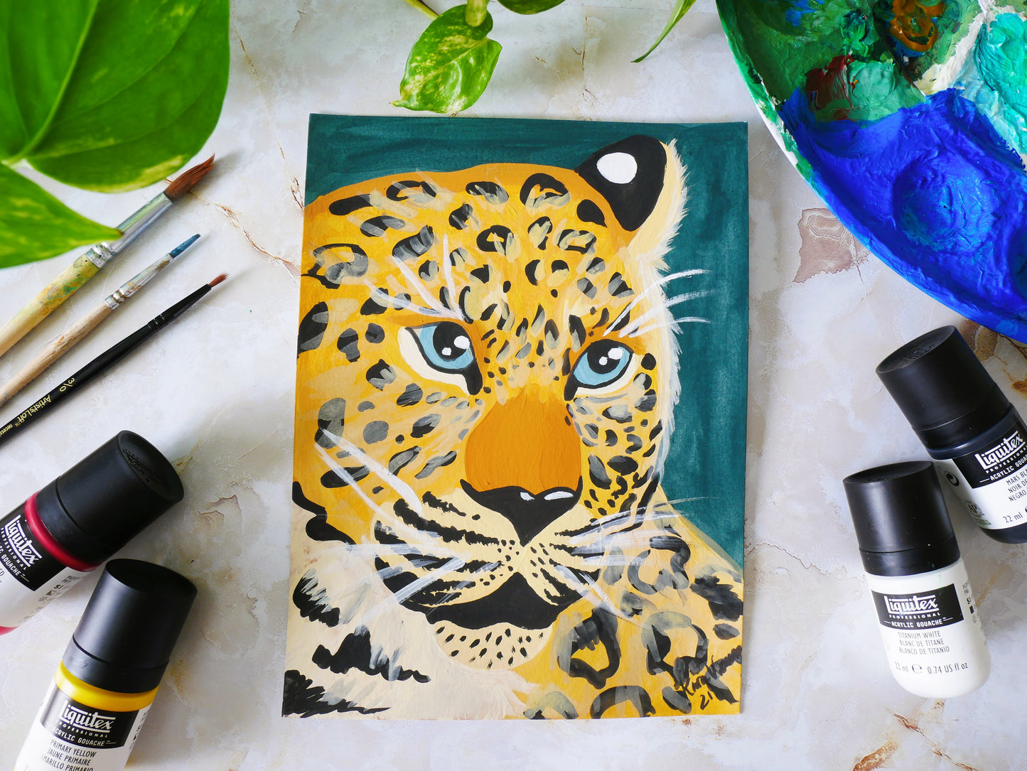 amur leopard gouache painting flat lay with paints and paintbrushes to show size