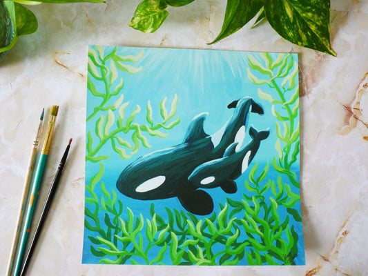 orca whale with calf swimming through kelp forest fine art print displayed next to paint brushes for size reference
